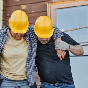 Construction worker helping an injured colleague walk at a worksite